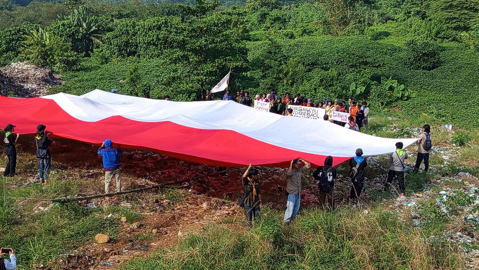 Puluhan mahasiswa pecinta alam (Mapala) se-Banten membentangkan bendera sang saka Merah Putih di tengah tumpukan sampah TPA Bangkonol. (Sumber Istimewa )