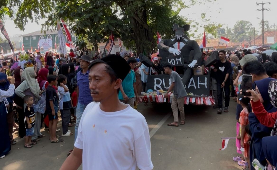 Suasana Warga Menes menampilkan Ornamen satir tikus raksasa bertuliskan “Rp 40 Miliar Runtah (Sampah)” di acara karnaval pada perayaan HUT RI ke-80 tahun.