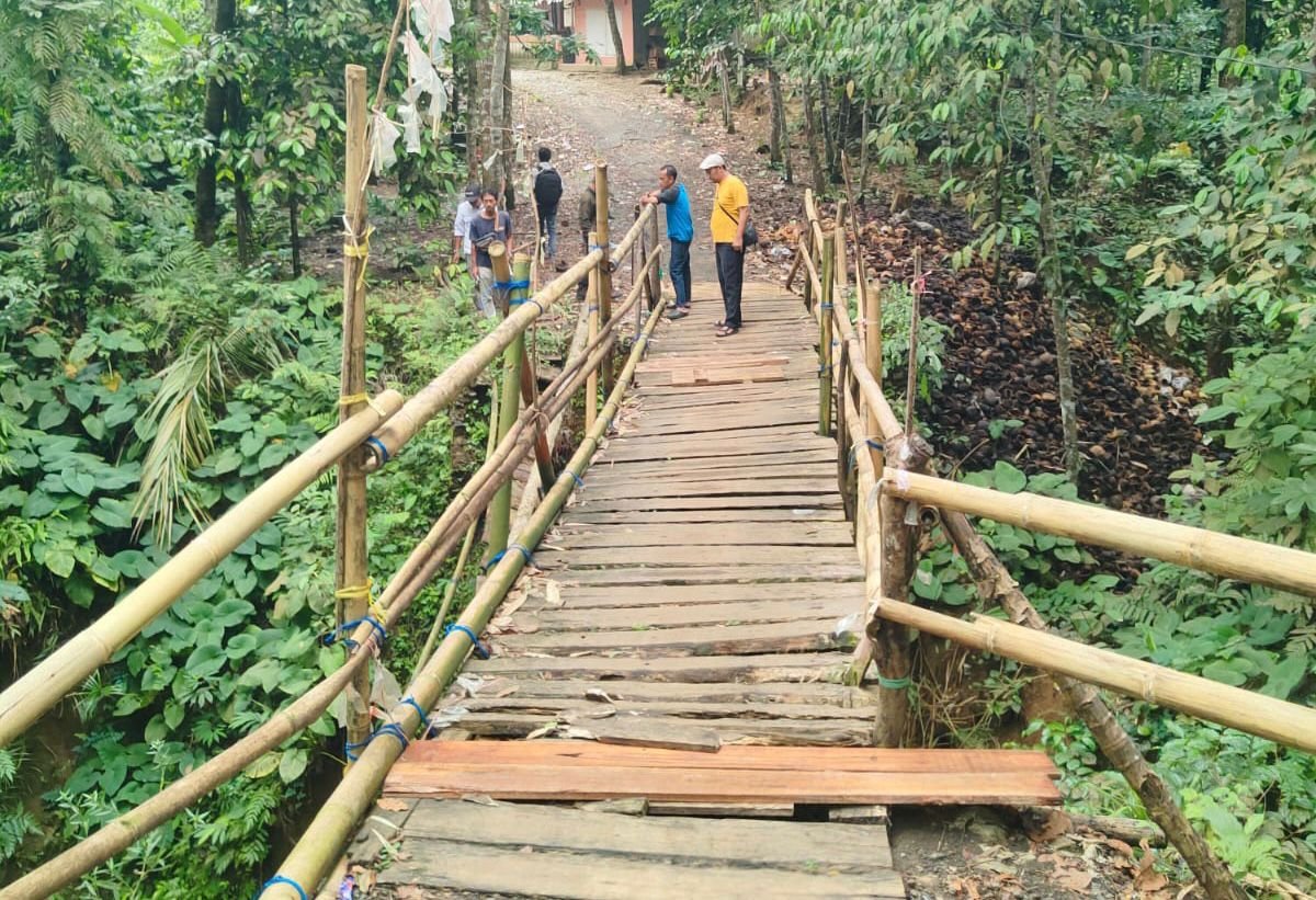 Caption : Salah seorang warga saat melintasi jembatan di Kampung Sarewu–Pasirsalinten, Desa Citaman, Kecamatan Jiput, Kabupaten Pandeglang.