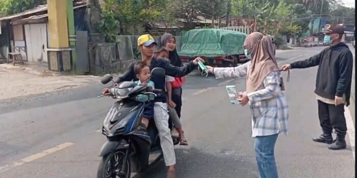 Caption: Puskesmas Kecamatan Labuan, Kabupaten Pandeglang, Banten, membagikan masker kepada para pengendara yang melintas di Jalan Raya Labuan.