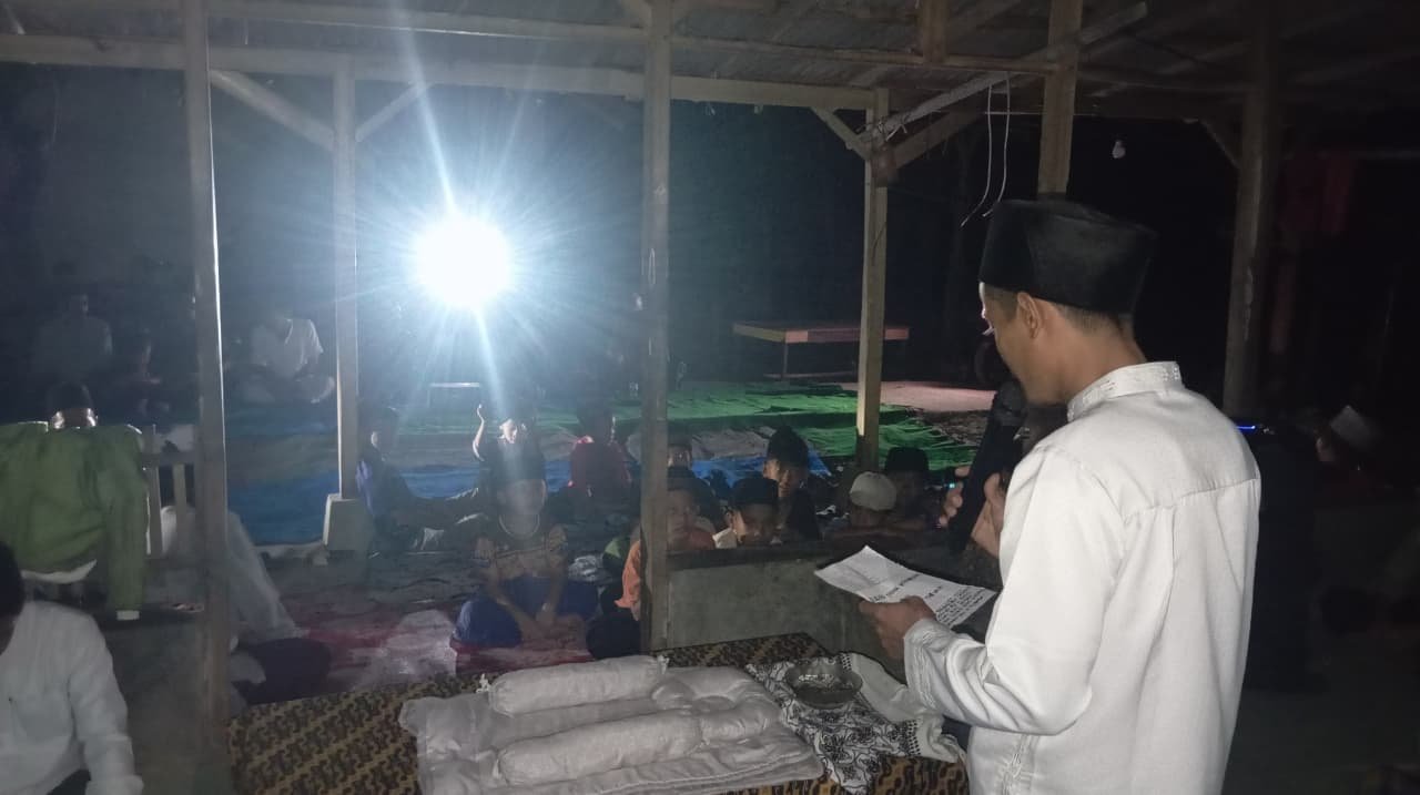 Caption : Seorang warga memanfaatkan lampu sepeda motor sebagai penerangan saat menggelar acara tasyakuran di Kampung Jalan Lempeung, Desa Cilegong Ilir, Kecamatan Banjarsari, Kabupaten Lebak, Banten, akibat pemadaman listrik.